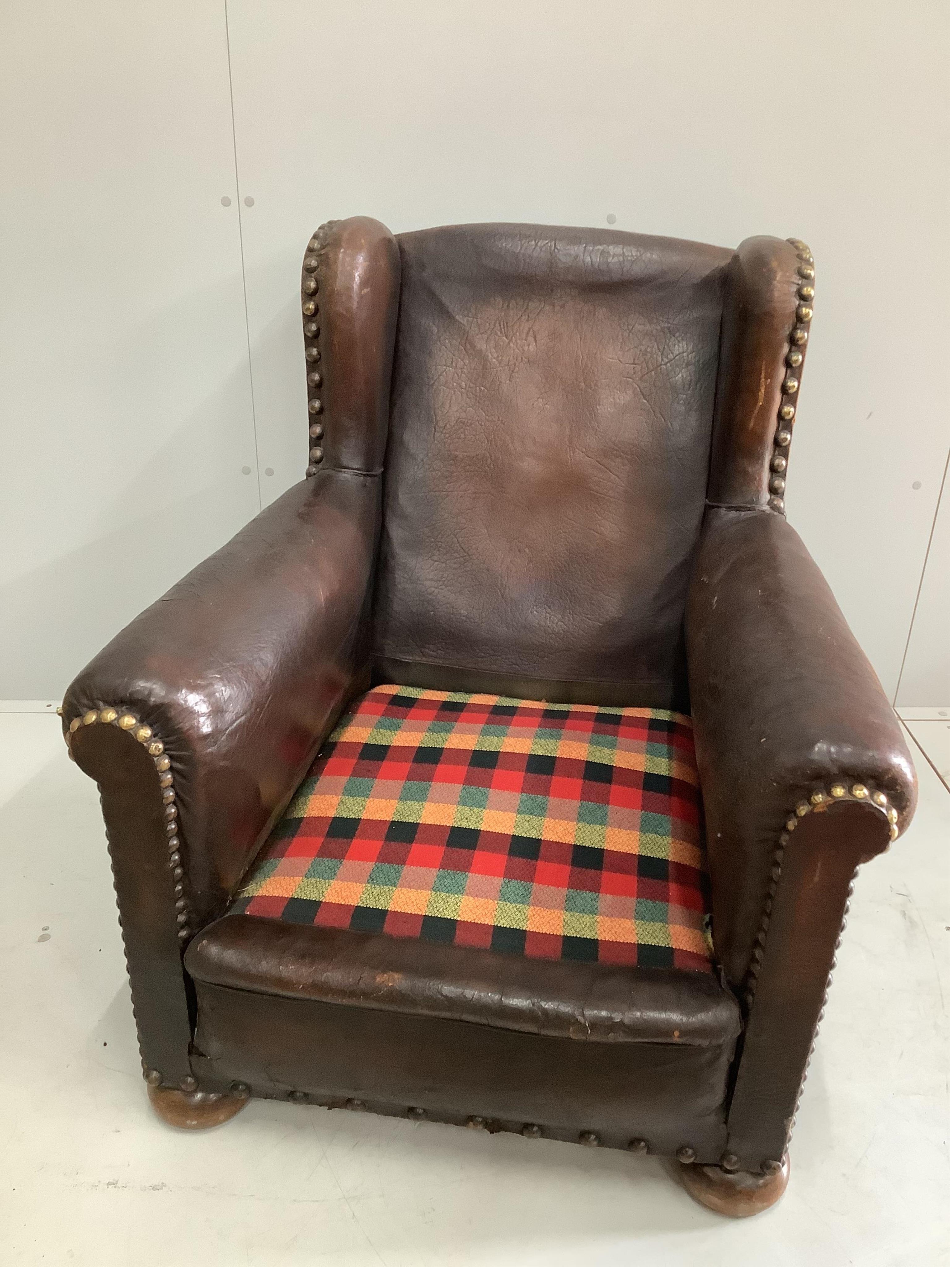 An early 20th century studded tan leather club armchair, width 84cm, depth 90cm, height 92cm. Condition - fair